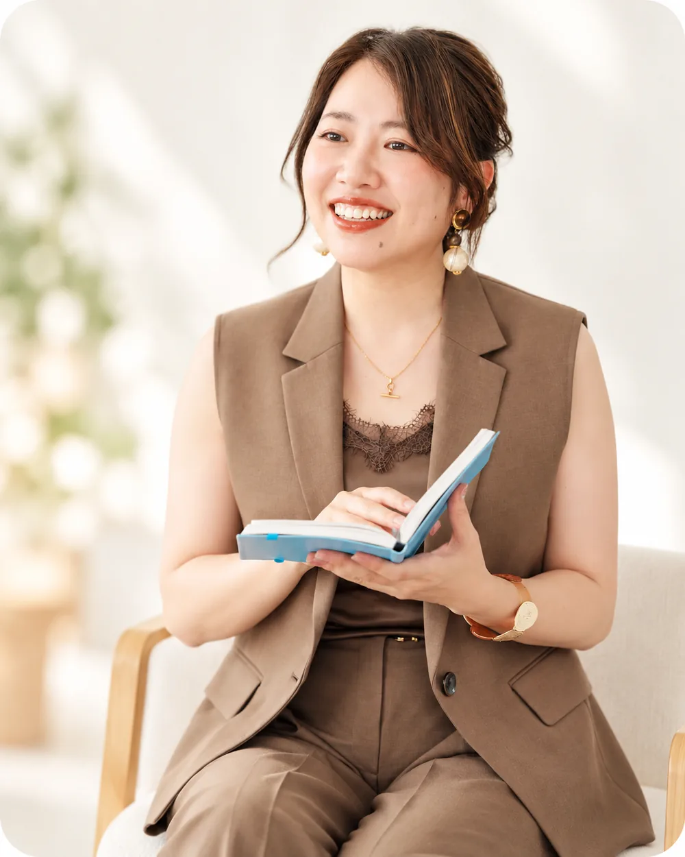 自然光の差し込む室内で、ノートを手に微笑むGrace Lifedesign Lab. 志穂さんの写真